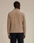 Back view of a man wearing a beige suede jacket and dark formal pants