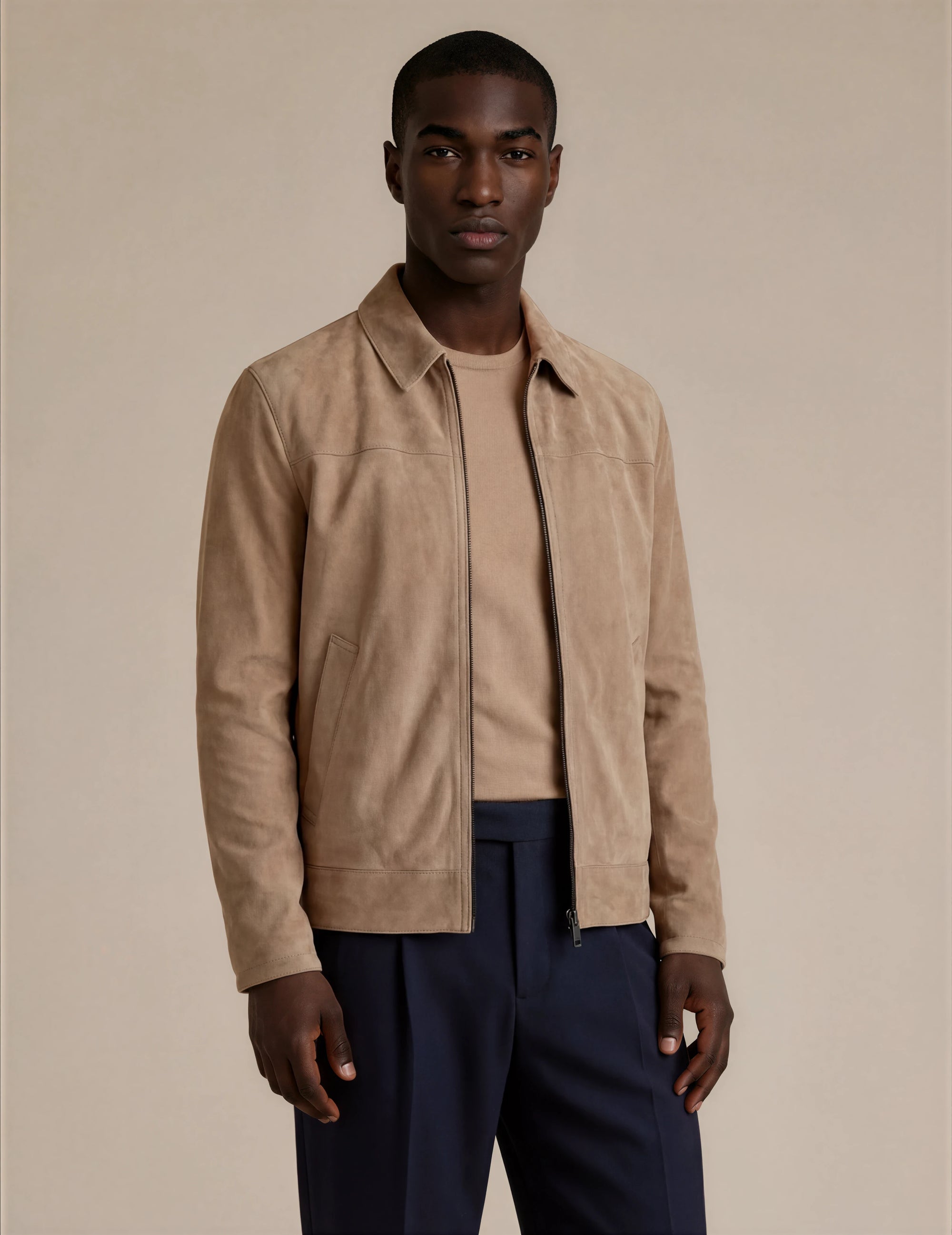 Man wearing a beige suede jacket, beige shirt and dark formal pants 